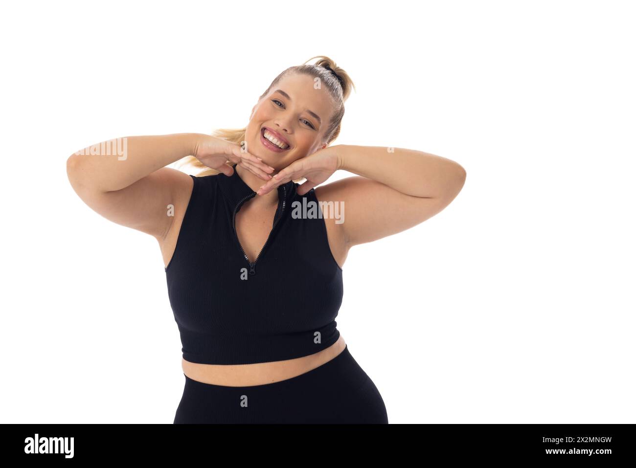 Caucasian young female plus size model poses with hands under chin, smiling, copy space Stock Photo