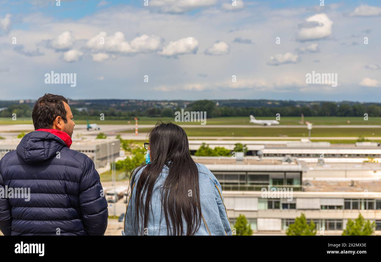 Zwei Menschen beobachten auf dem Besucherhügel des Flughafen München landende Flugzeuge. (Halbergmoos, Deutschland, 29.05.2022) Stock Photo
