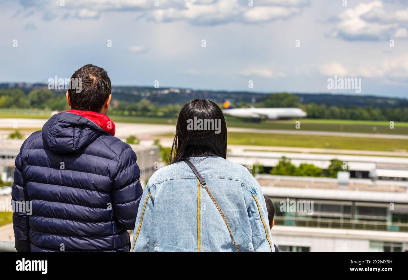 Zwei Menschen beobachten auf dem Besucherhügel des Flughafen München landende Flugzeuge. (Halbergmoos, Deutschland, 29.05.2022) Stock Photo