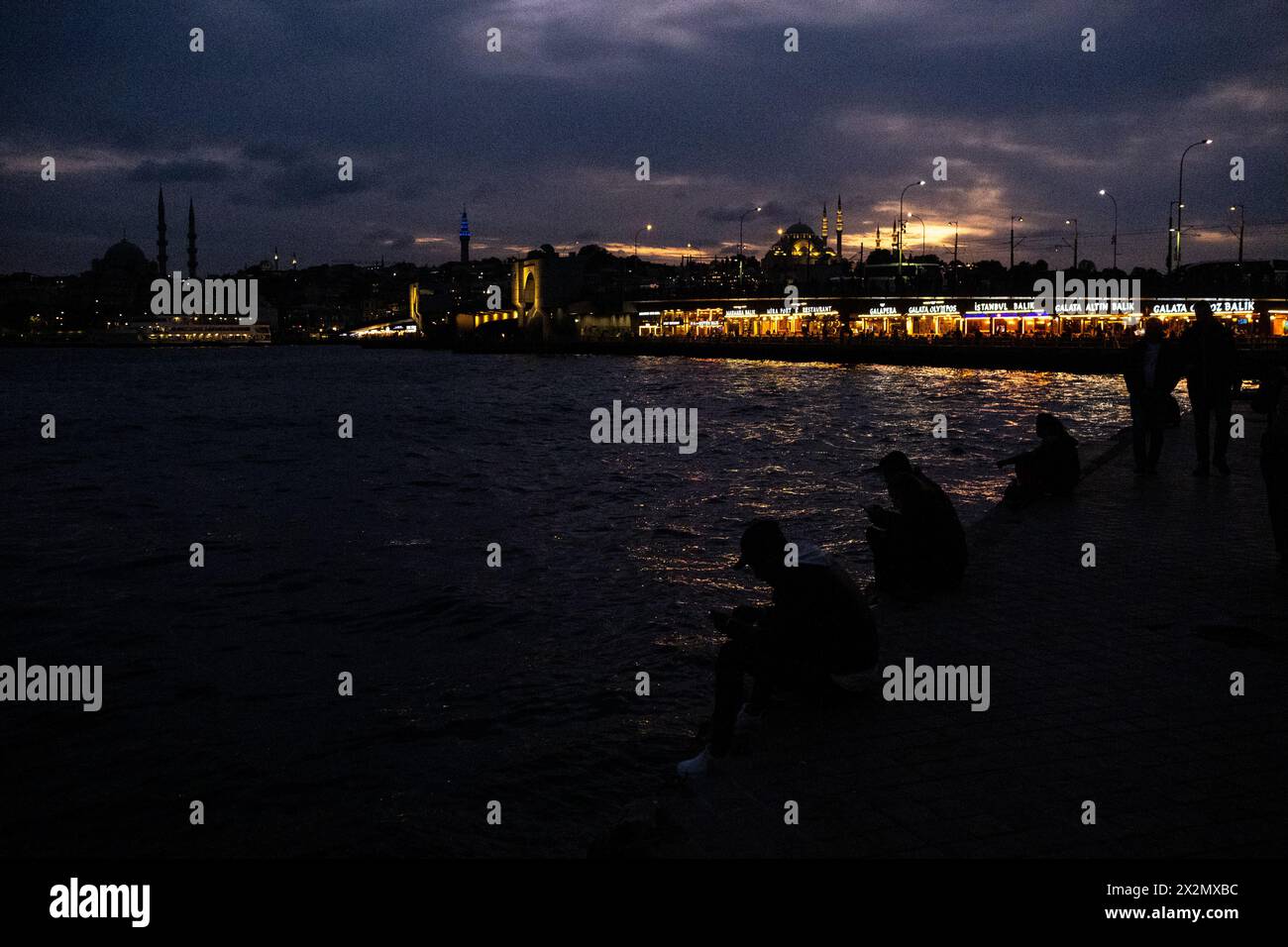 The Galata Bridge on the estuary of the Golden Horn at dusk, linking the districts of Sultanahmet and Galata with the New Mosque (Yeni Cami or Valide Stock Photo