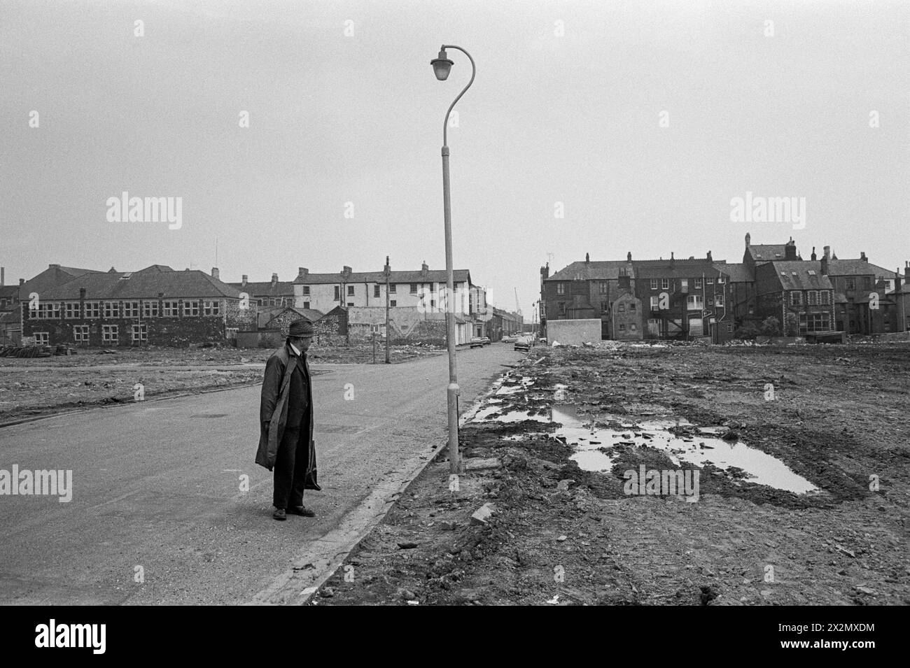 In 1974 a local resident surveys the destruction after once-familiar streets had been reduced to rubble during the large-scale redevelopment in Pill, Newport, South Wales. Stock Photo
