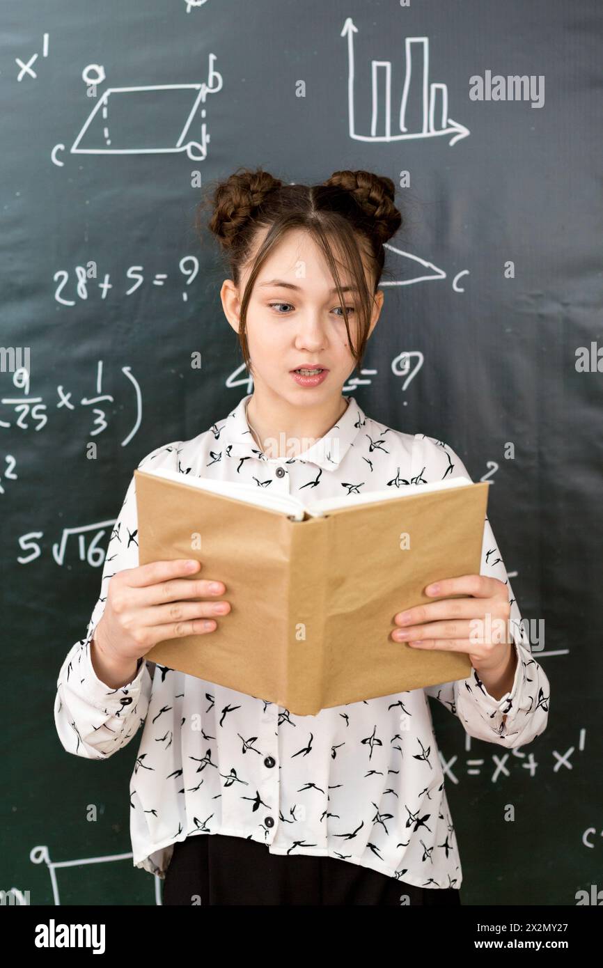 Emotional girl schoolgirl with open book in her hands Stock Photo - Alamy