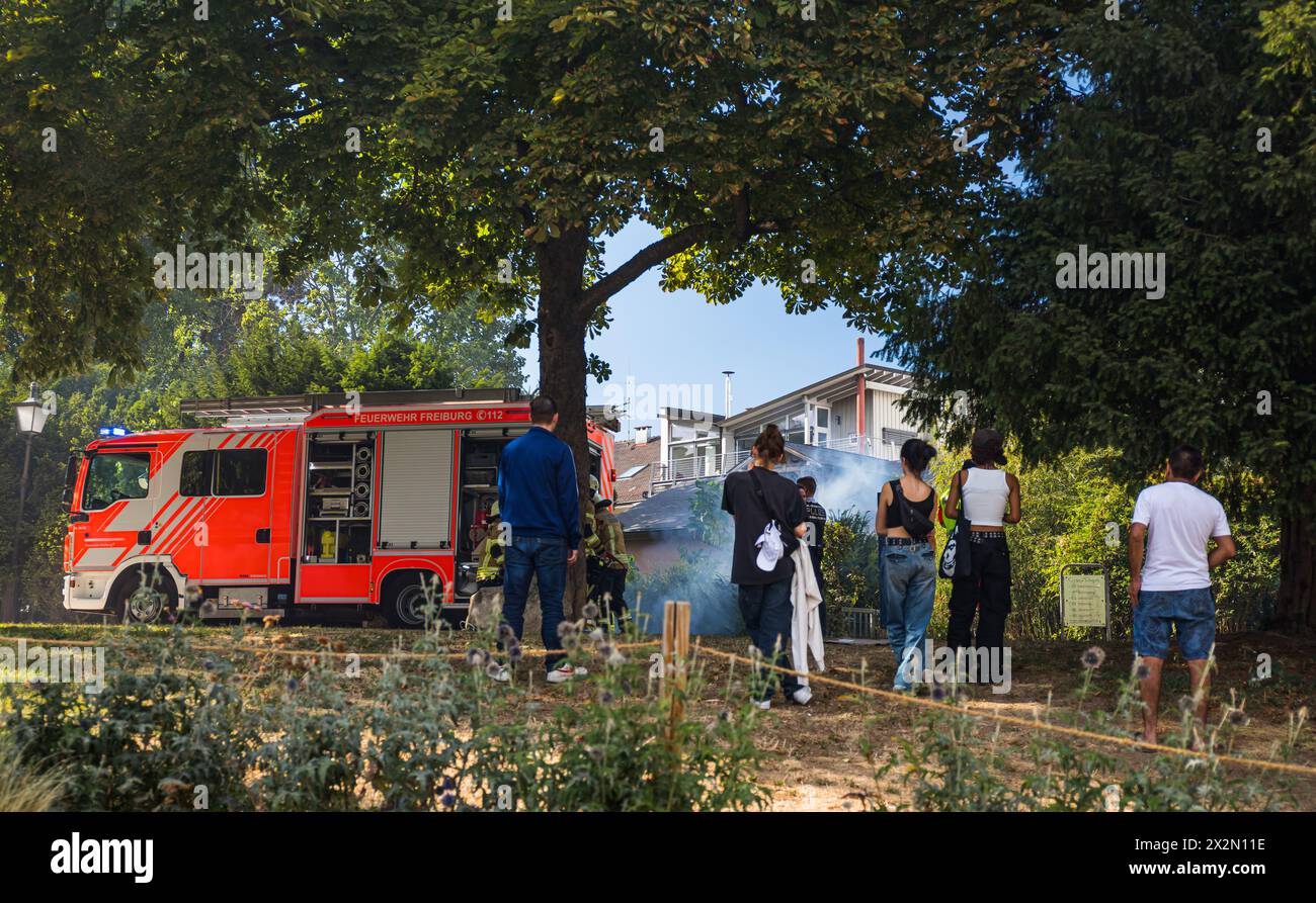 Trotz starker Rauchentwicklung wegen eines Containerbrandes, schauen zahlreiche Personen der Feuerwehr Freiburg im Breisgau bei den Löscharbeiten zu. Stock Photo