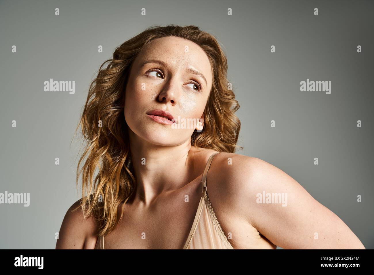 A beautiful woman in a tan dress poses gracefully for a portrait in natural light. Stock Photo