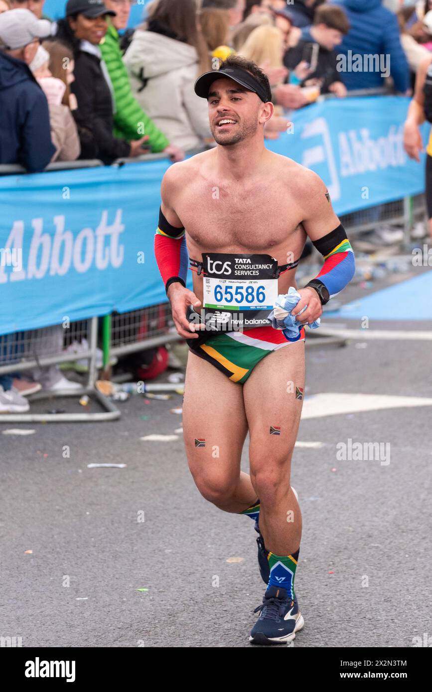 Dillon Ribeiro participating in the TCS London Marathon 2024 passing through Tower Hill, London, UK, wearing just swimming trunks Stock Photo