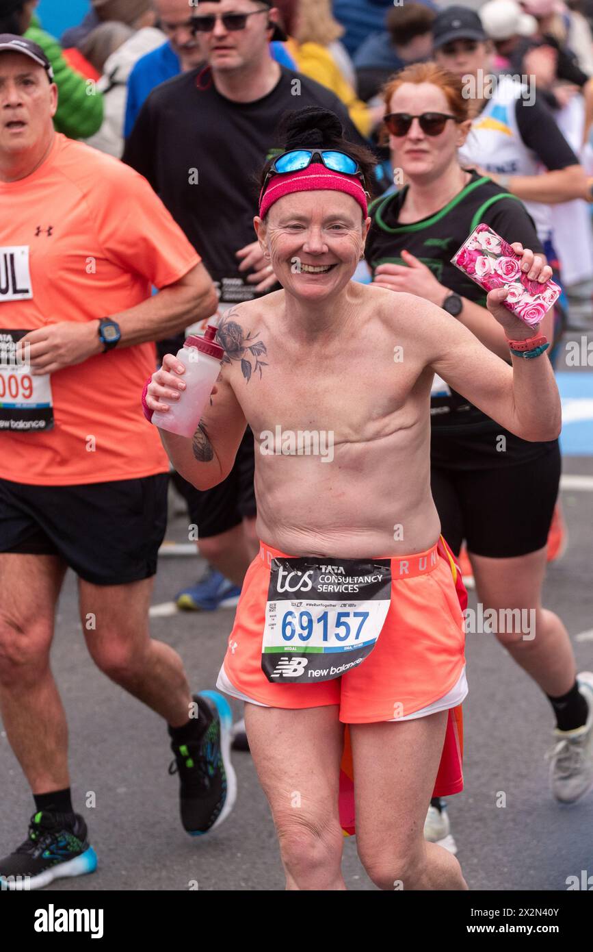 Louise Butcher participating in the TCS London Marathon 2024 passing through Tower Hill, London, UK, topless showing double mastectomy scars Stock Photo