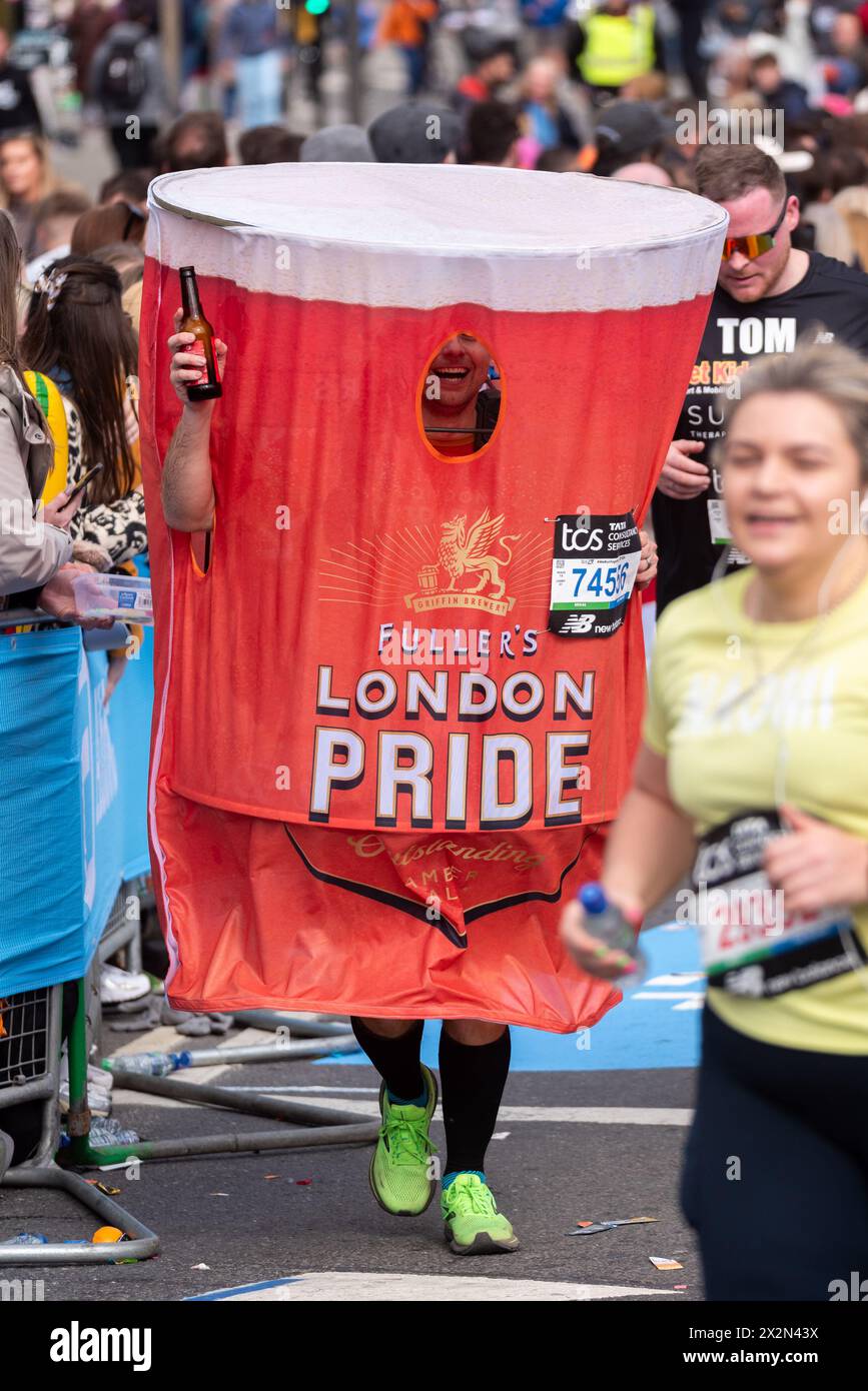 Scott Lofthouse participating in the TCS London Marathon 2024 passing through Tower Hill, London, UK, wearing Fullers London Pride pint glass costume Stock Photo