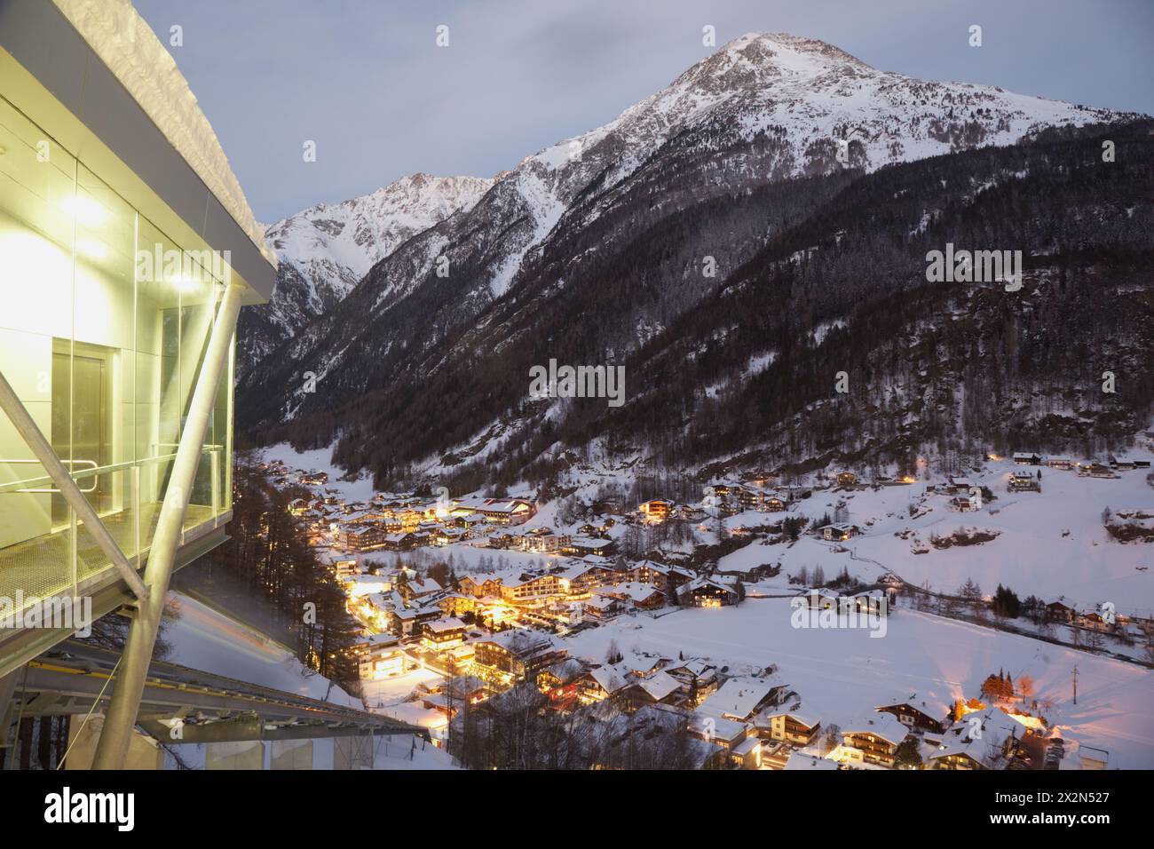 View from funicular station at village in valley, filled with evening lights Stock Photo