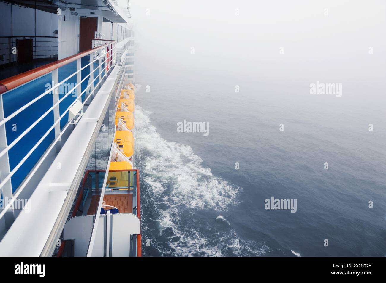 Empty deck and railing of beautiful cruise ship; thick fog over sea ...