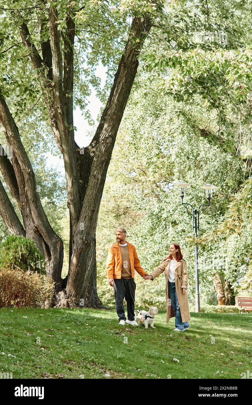 A couple takes a leisurely walk with their dog in a lush park Stock ...