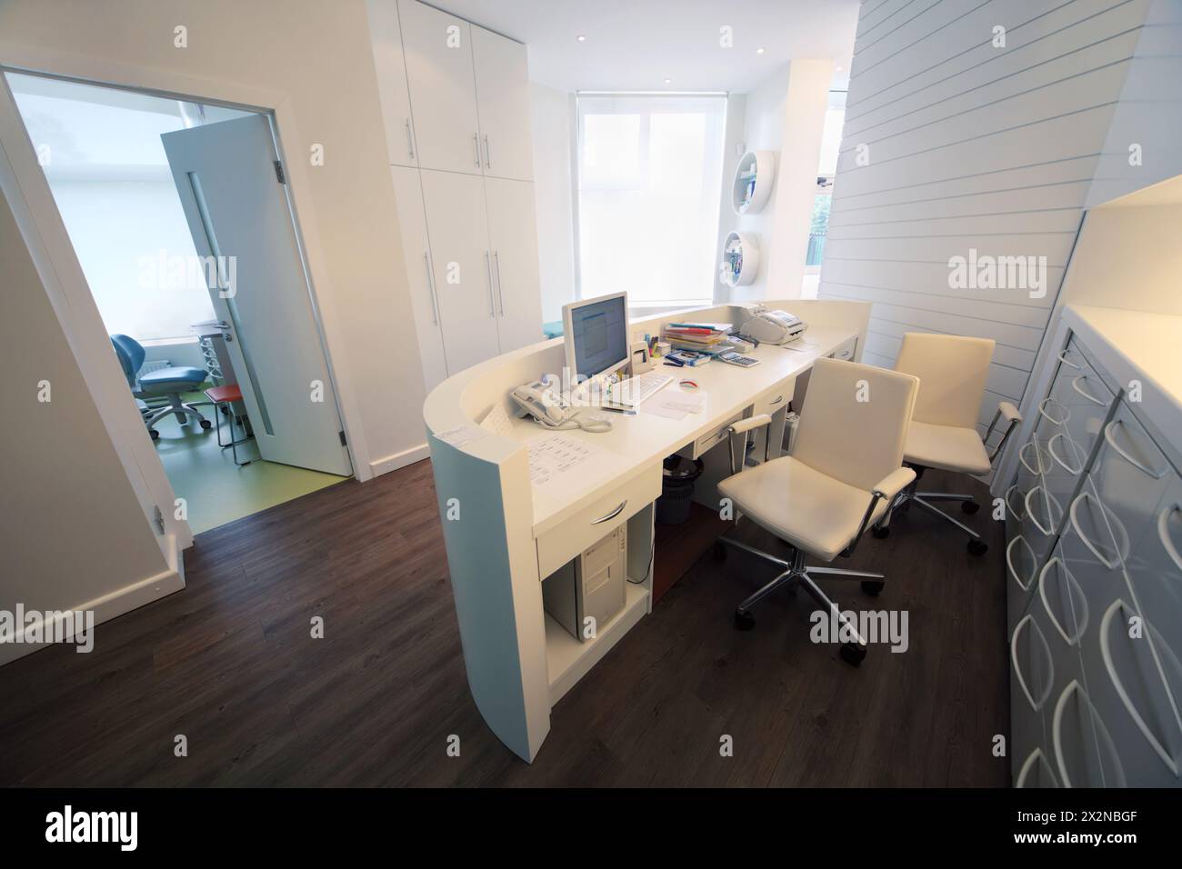 Empty lit reception area in dental clinic. Working place at table with ...