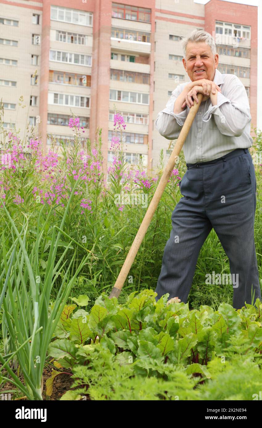 Grandfather leaning on shovel in garden Stock Photo