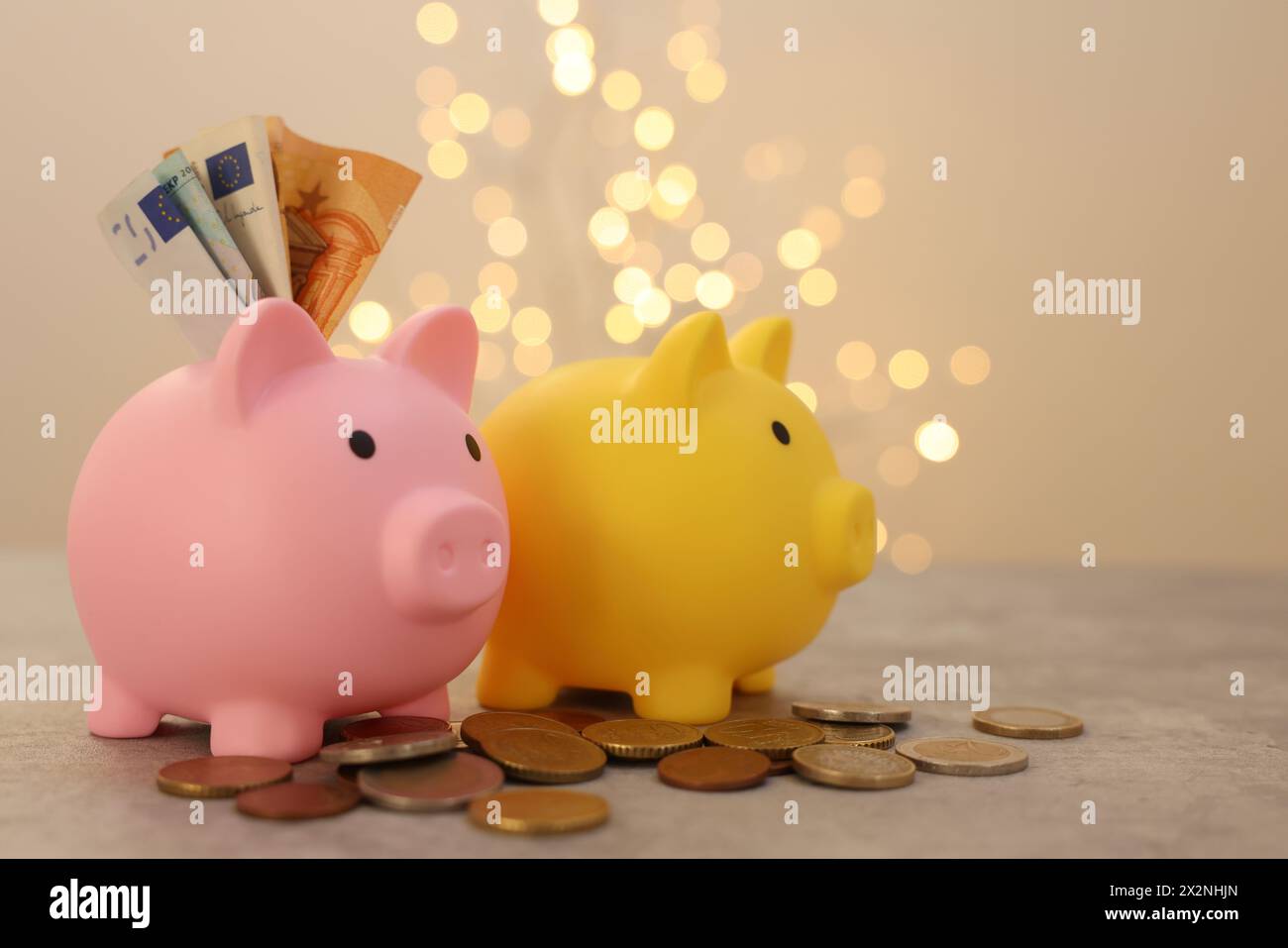 Piggy banks, euro banknotes and coins on grey table against blurred ...