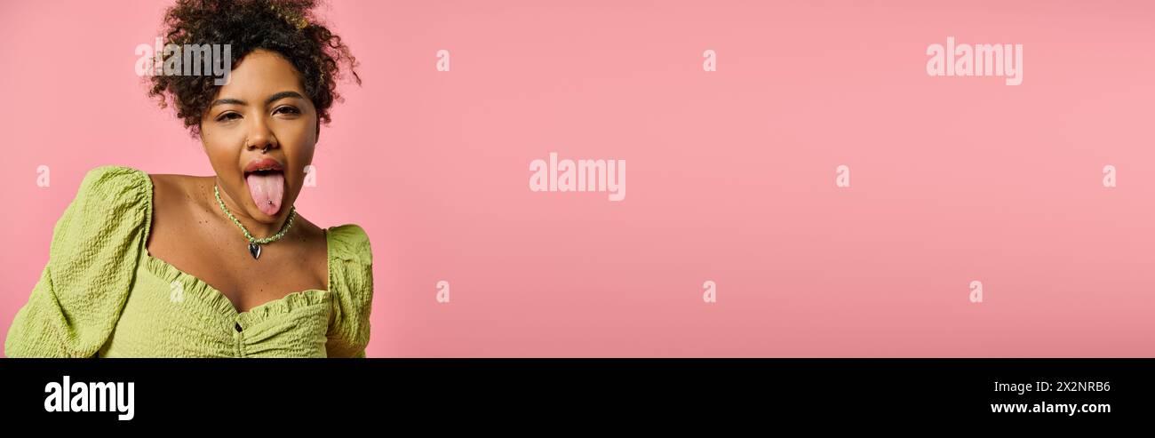 Stylish African American woman sticking out tongue against pink ...