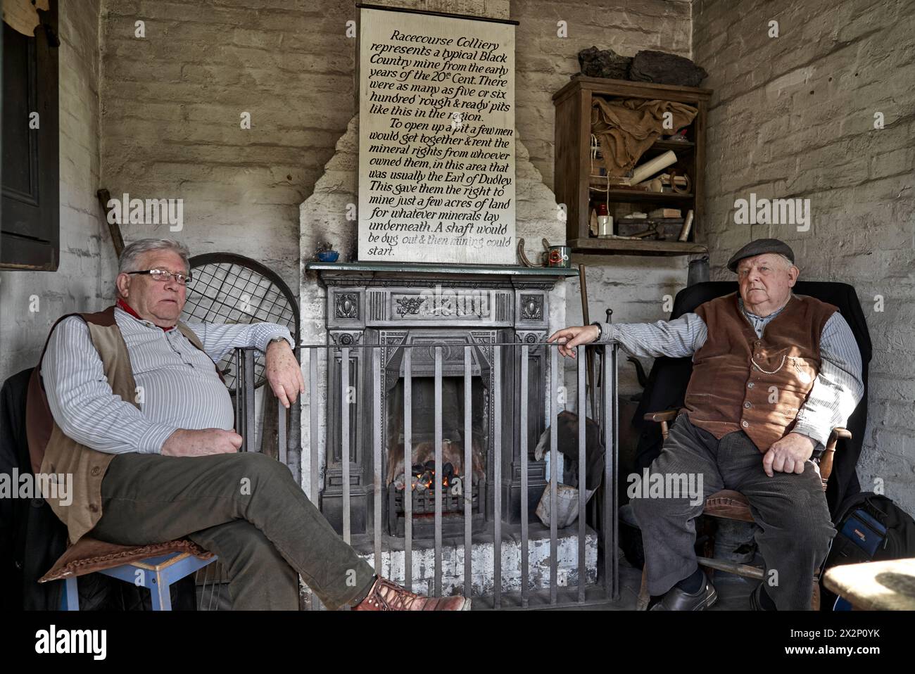 Black Country Museum. Fireplace and senior men in a preserved 1800's early 1900's cottage type home  Dudley England UK Stock Photo