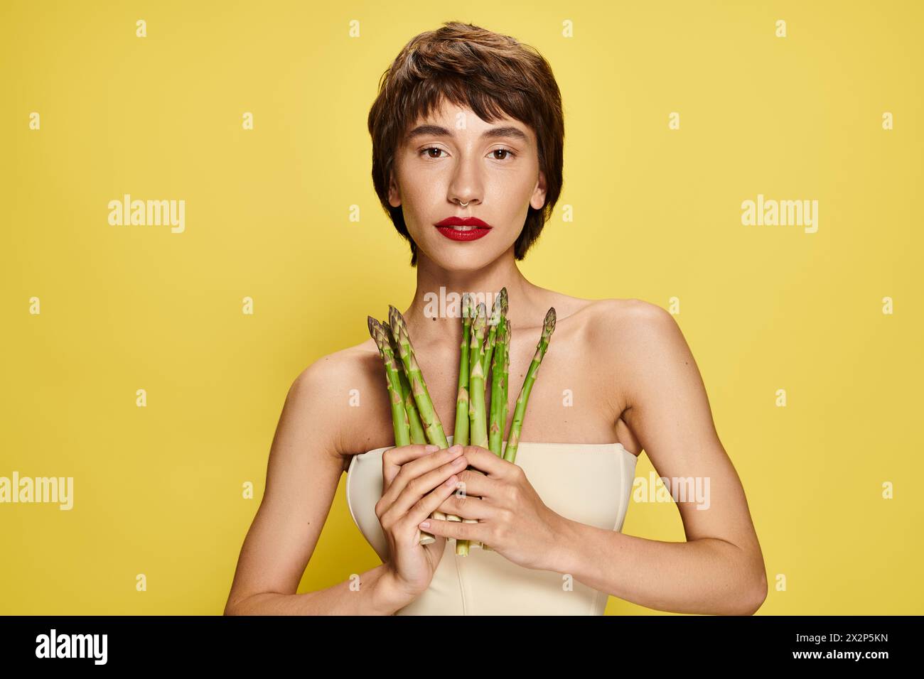 A young woman holding a bunch of asparagus in front of her face. Stock Photo