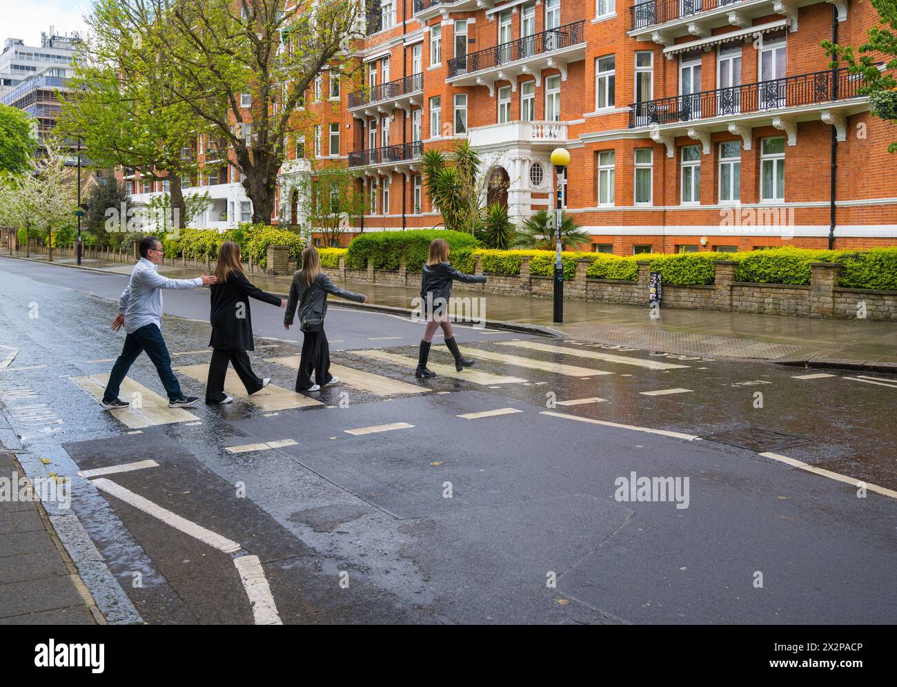 Three young women and a man re-enact the Beatles Abbey Road album cover at the zebra crossing at Abbey Road Studios. St John's Wood, London England UK Stock Photo