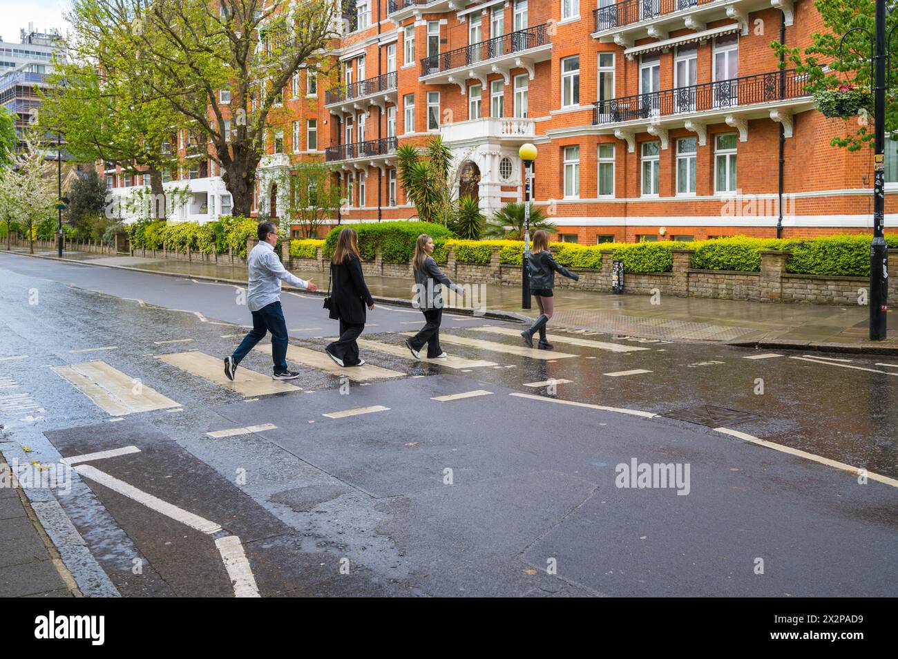 Three young women and a man re-enact the Beatles Abbey Road album cover at the zebra crossing at Abbey Road Studios. St John's Wood, London England UK Stock Photo