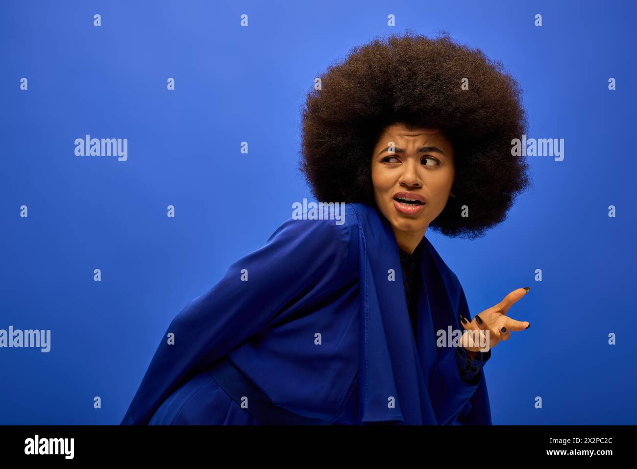 A stylish African American woman in trendy attire with curly hairdois making a funny face. Stock Photo