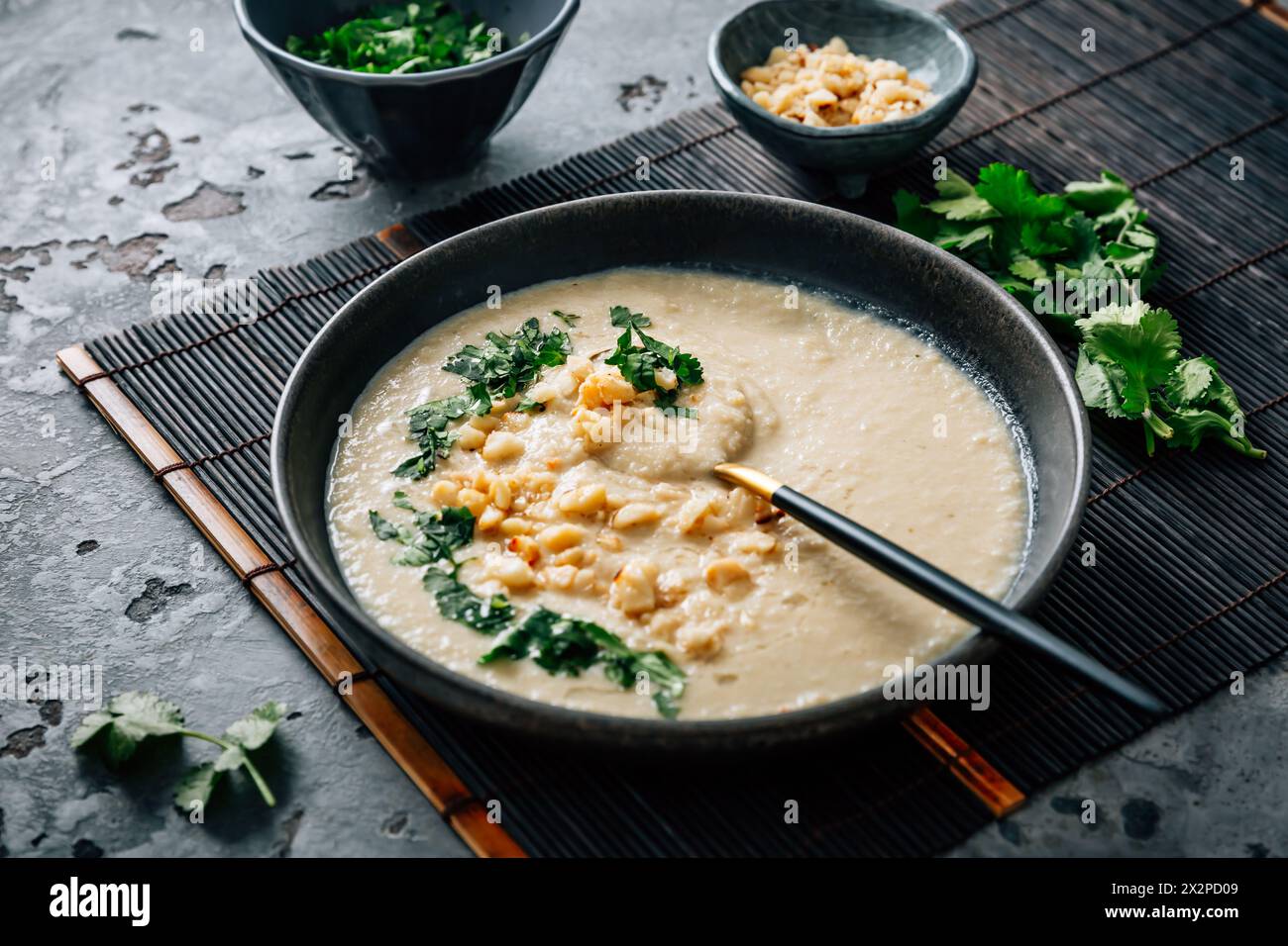 Spicy and creamy cauliflower and coconut soup with cilantro and macademia nuts Stock Photo