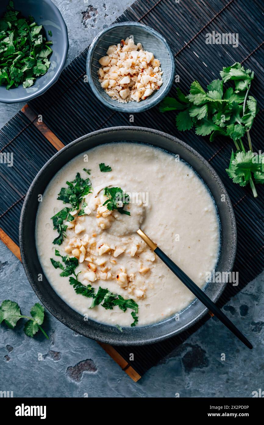 Spicy and creamy cauliflower and coconut soup with cilantro and macademia nuts Stock Photo