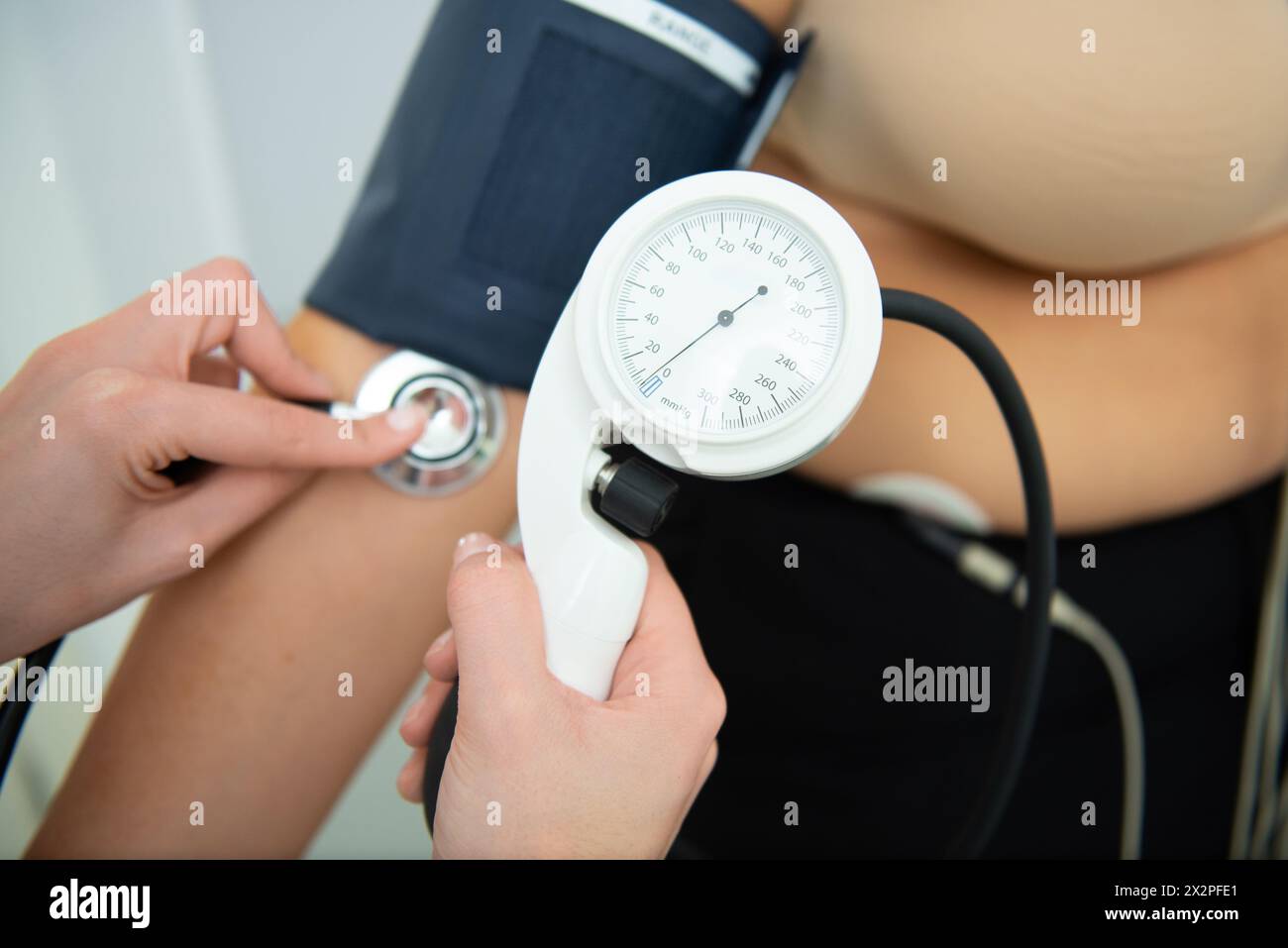 A healthcare professional administers a cardiology test with electrodes and blood pressure cuff. Stock Photo