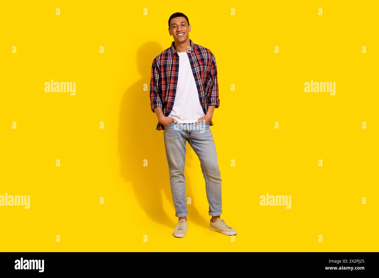 Full length photo of handsome stylish guy wear checkered shirt denim pants keep hands in pockets isolated on vivid color background Stock Photo