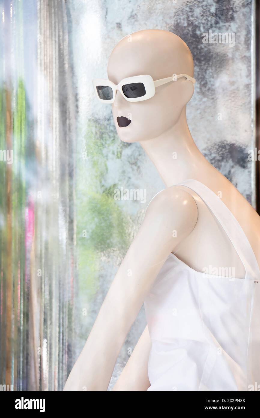 Belgrade, Serbia - April 3, 2024: One bald mannequin doll in white dress with reflections in the shop window of Max Mara store Stock Photo