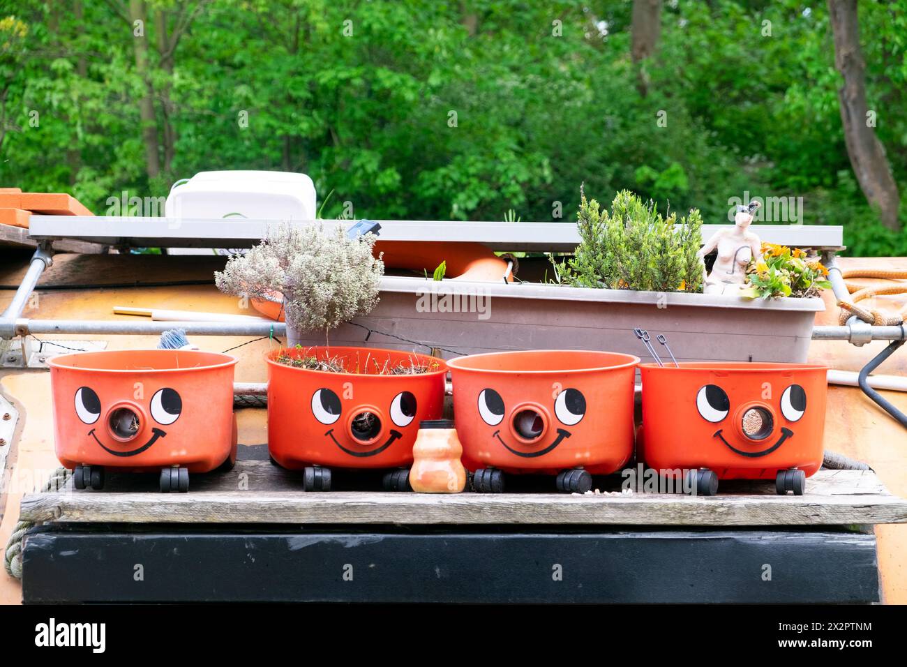 Recycled Henry vacuum cleaner bases reuse as garden pots containers on a canal houseboat roof in Hackney London England UK KATHY DEWITT Stock Photo