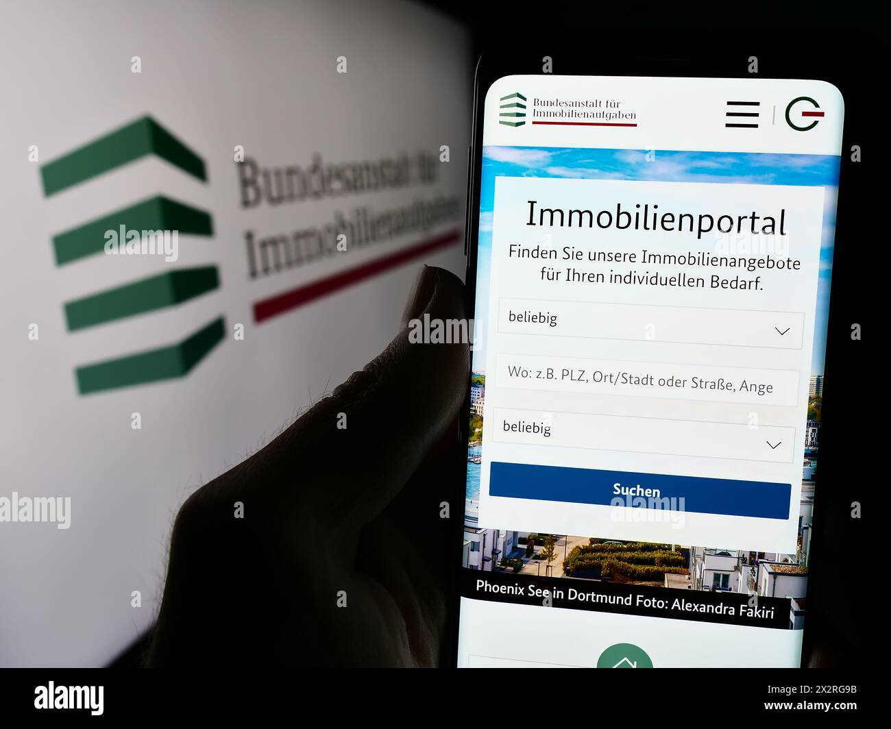 Person holding cellphone with webpage of German agency Bundesanstalt für Immobilienaufgaben (BImA) with logo. Focus on center of phone display. Stock Photo