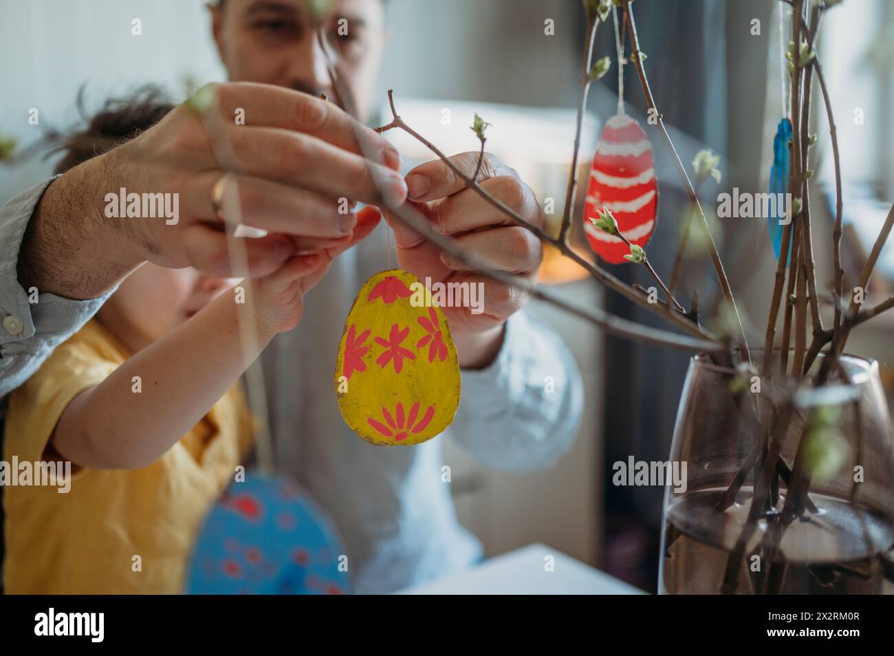 Father and son decorating painted Easter eggs on twigs Stock Photo
