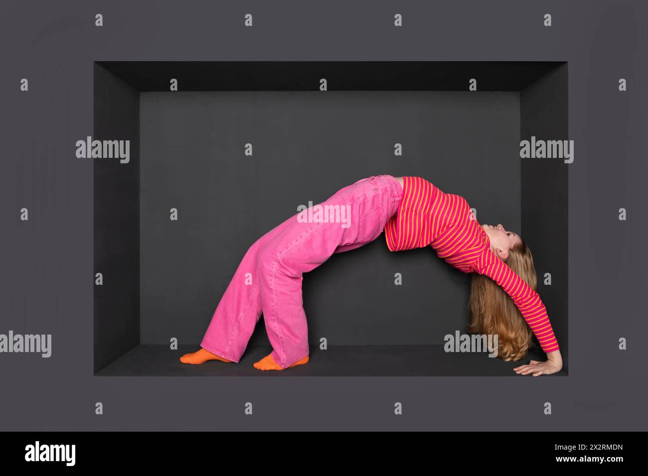 Teenage girl bending backward against black backward Stock Photo