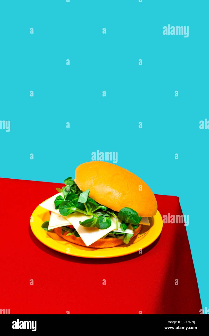 Chicken burger with cheese and lettuce on table against blue background Stock Photo