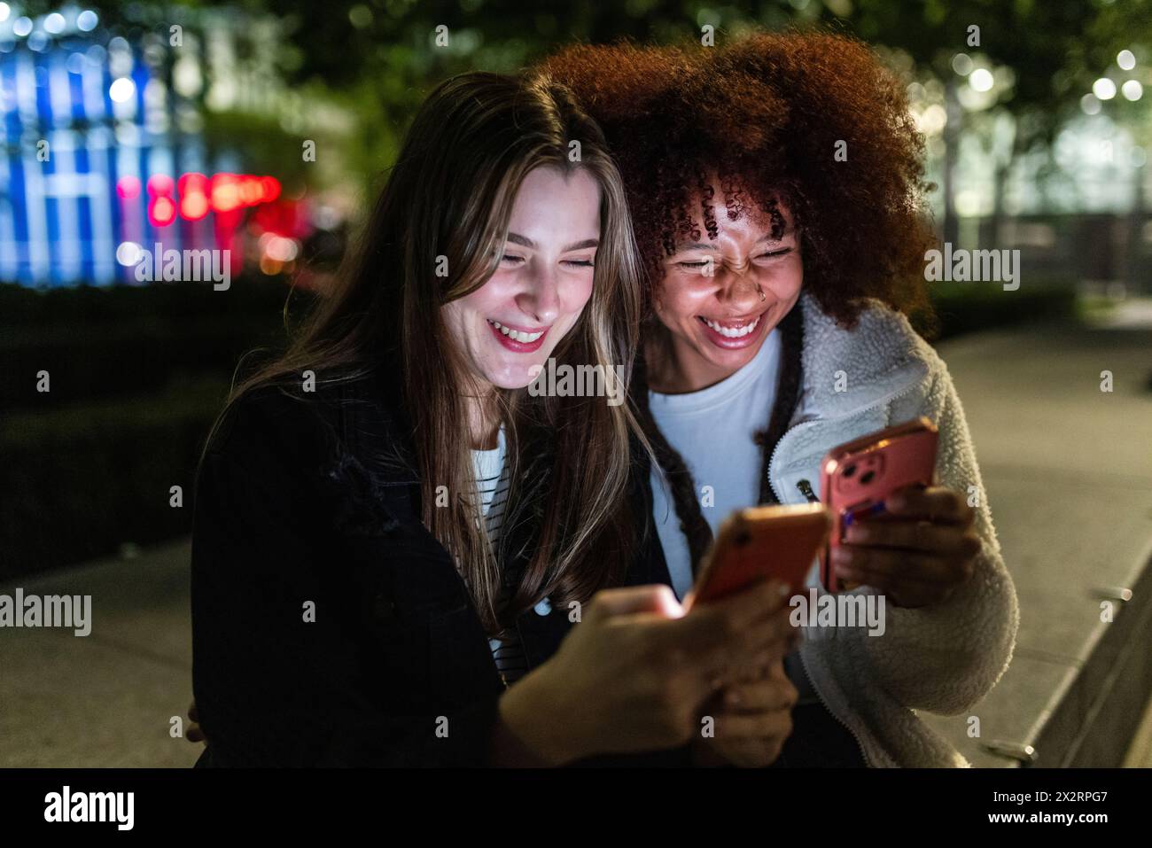 Happy young friends using smart phones at night Stock Photo