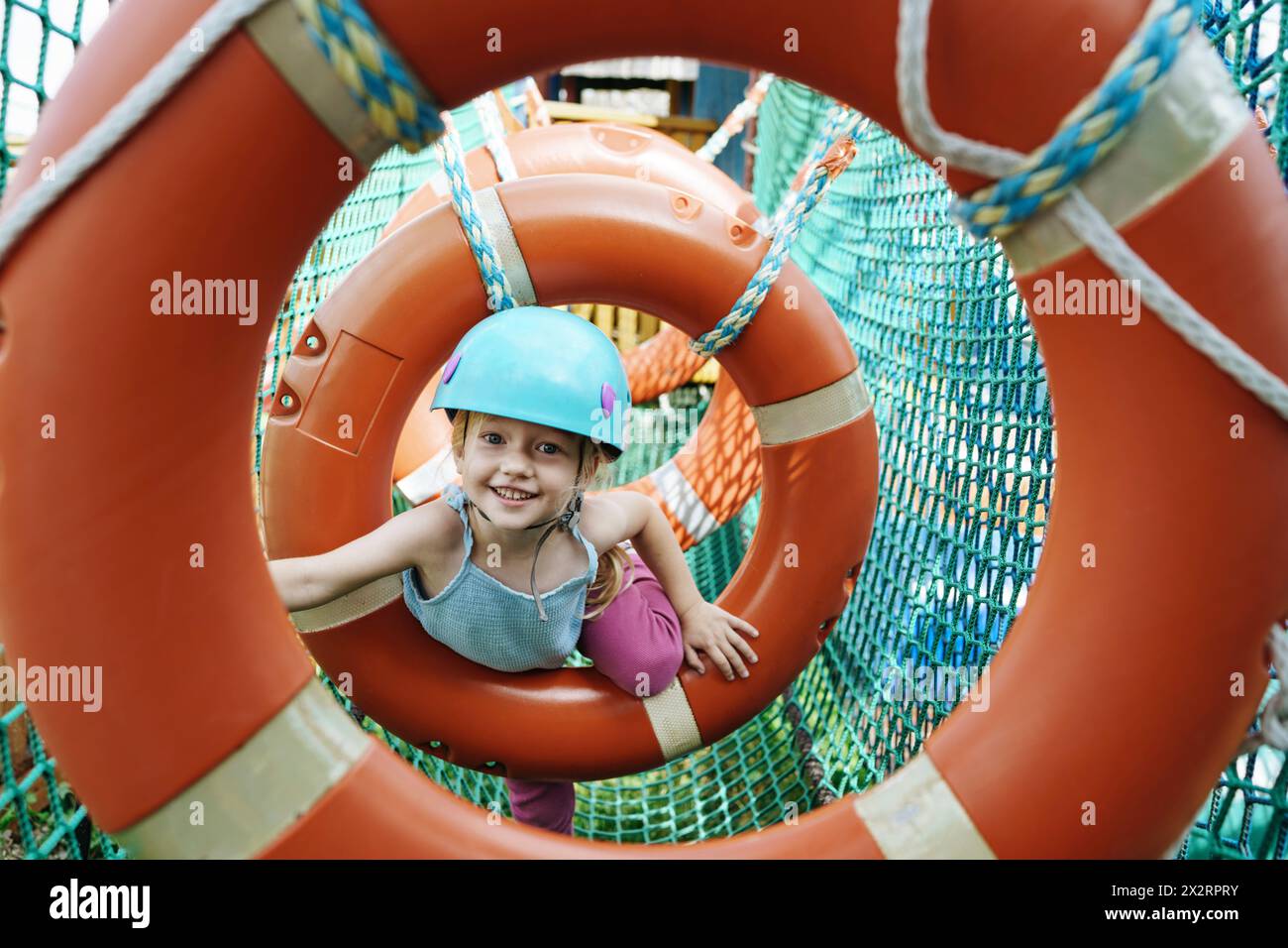 Smiling girl doing obstacle course at rope park Stock Photo