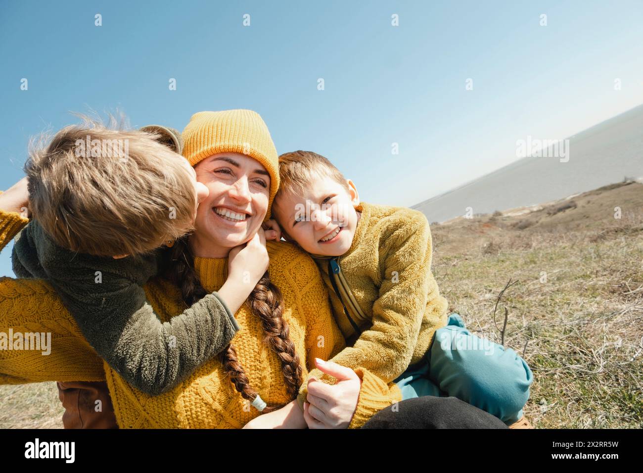 Happy woman spending leisure time with sons on hill at sunny day Stock Photo