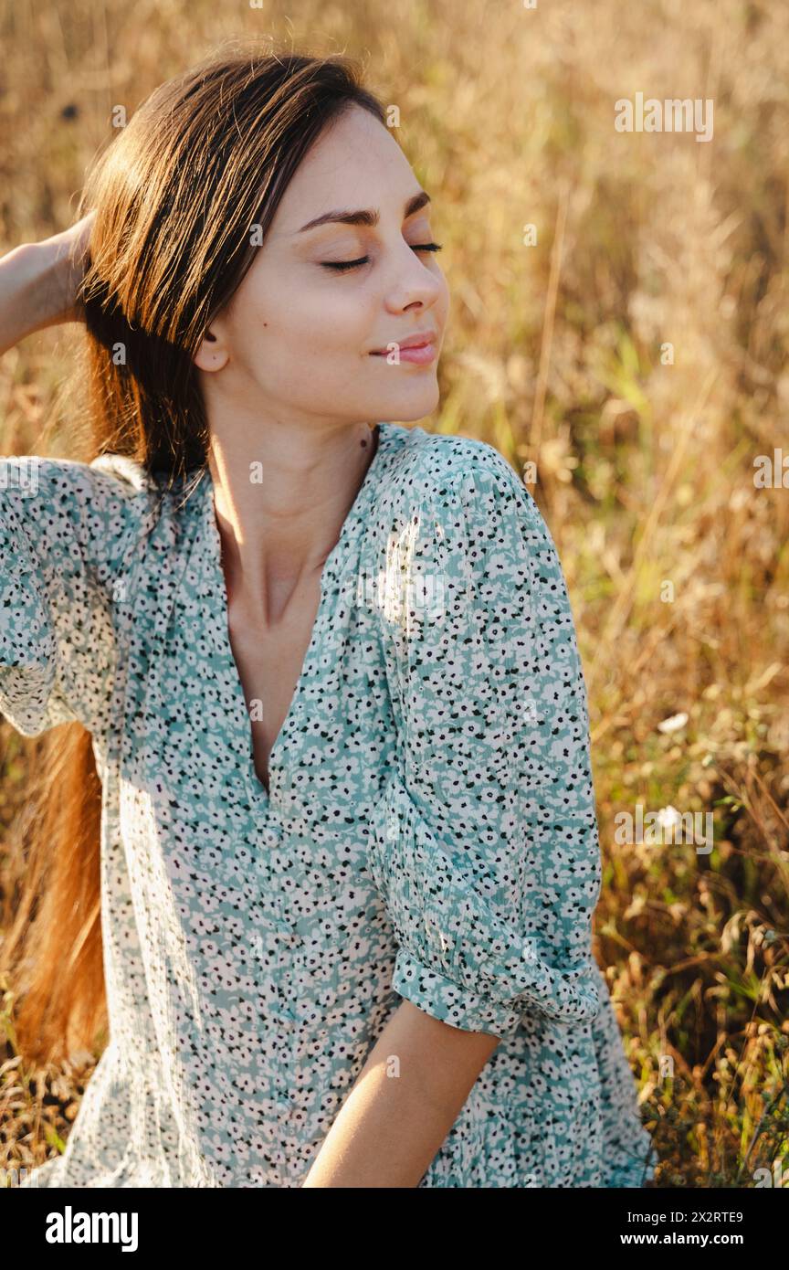 Beautiful woman sitting with eyes closed in meadow Stock Photo - Alamy