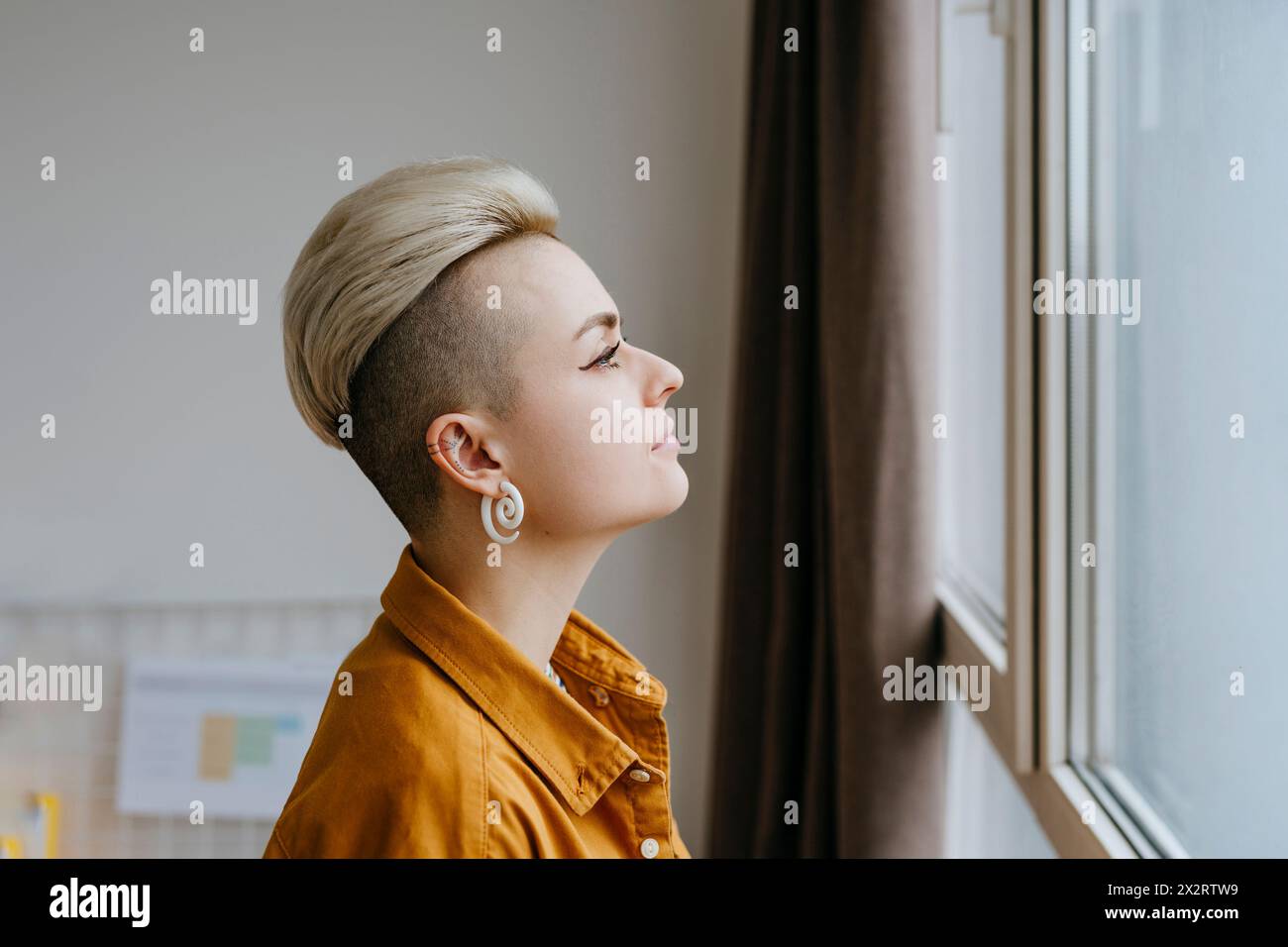 Lonely woman looking out of window at home Stock Photo