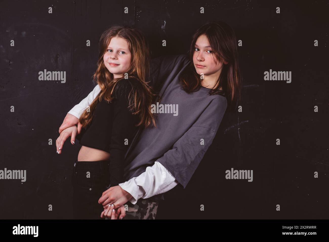 Smiling girls embracing in front of black background Stock Photo - Alamy