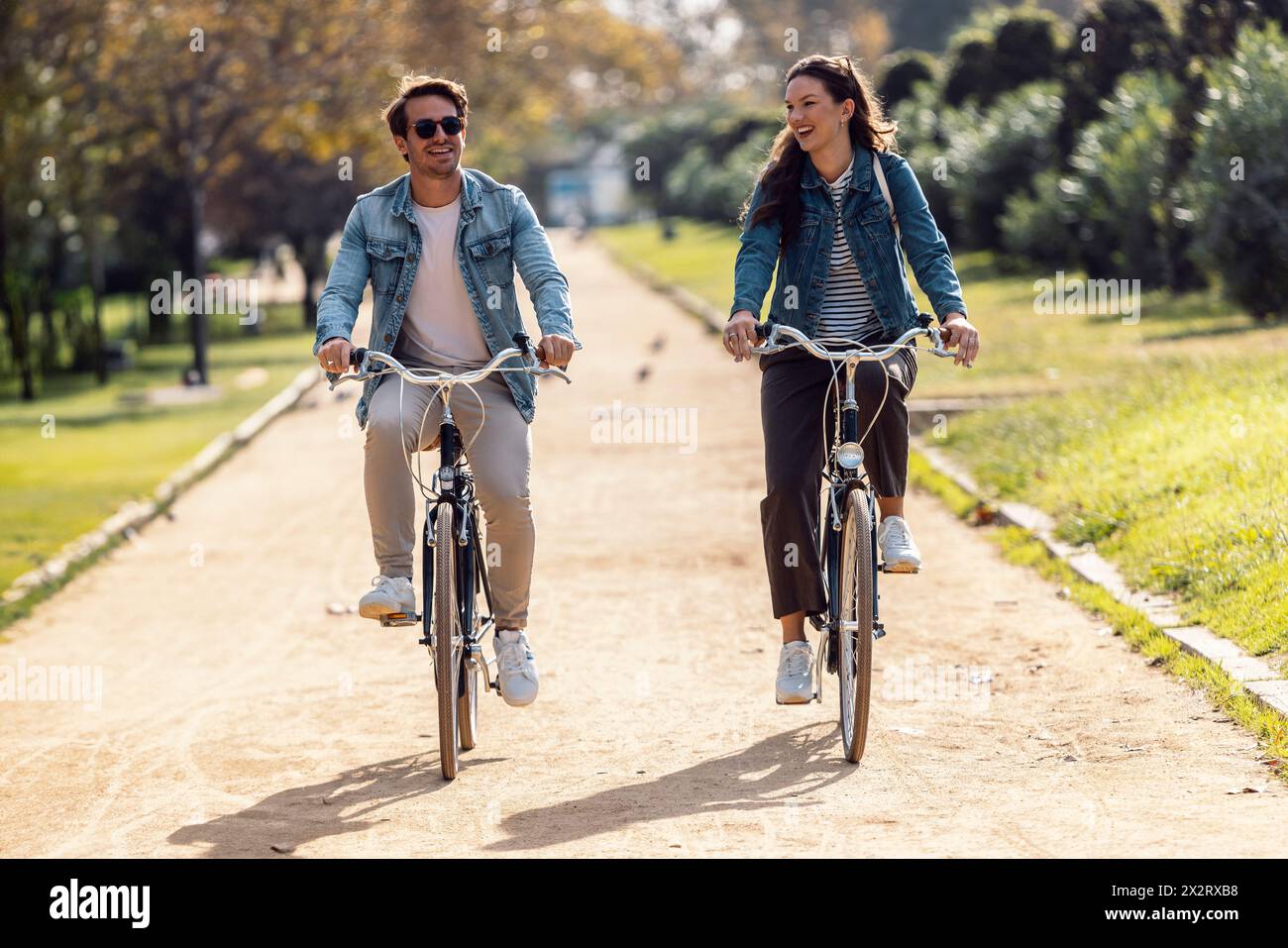 Happy couple cycling and having fun on footpath at park Stock Photo