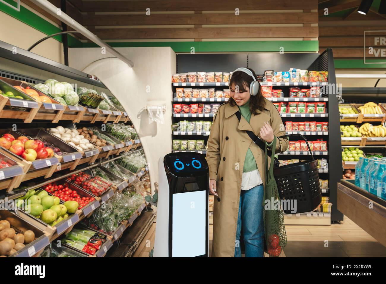 Smiling woman walking with smart robot assistant at grocery store Stock Photo