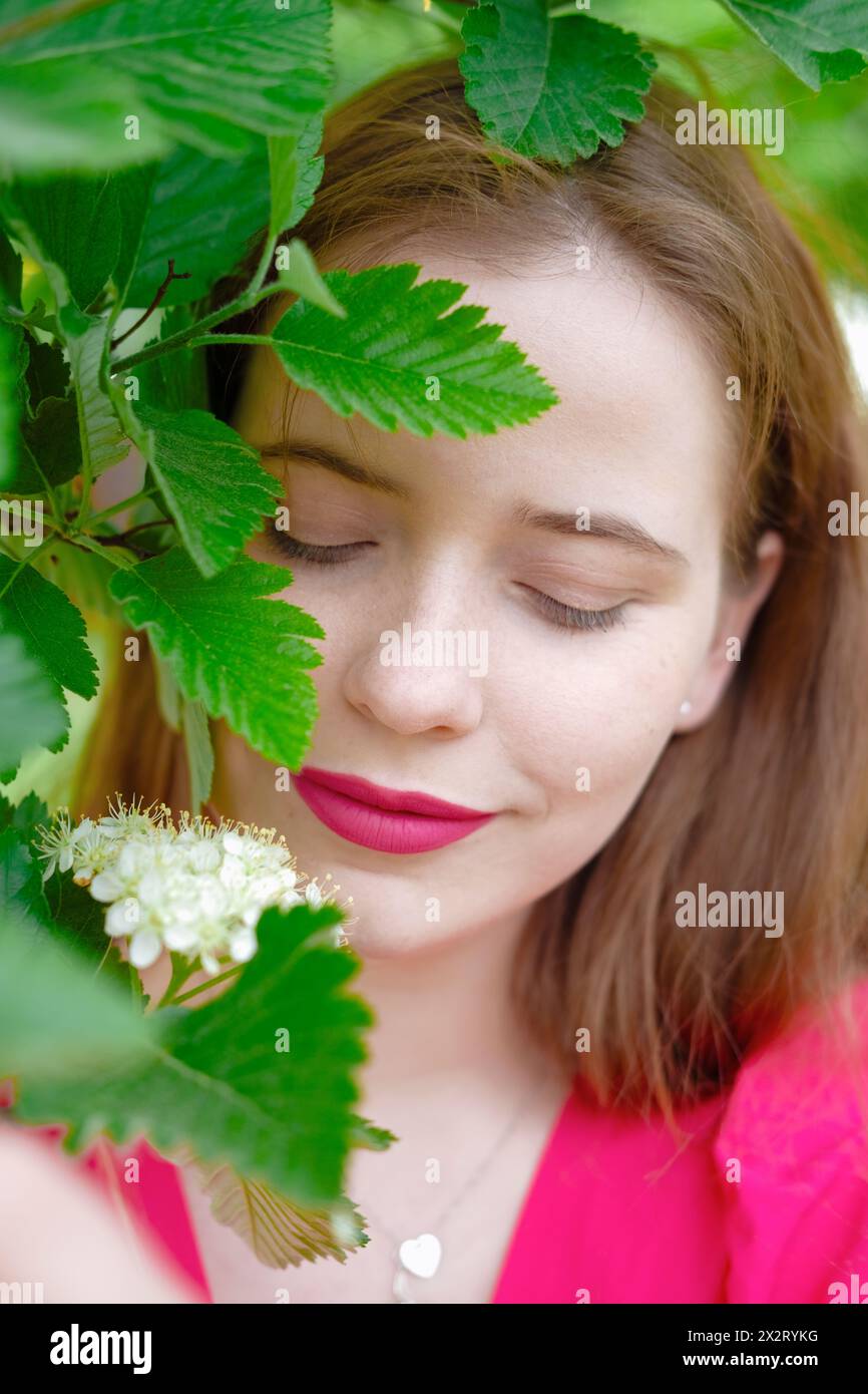 Beautiful woman with lipstick near plant at park Stock Photo