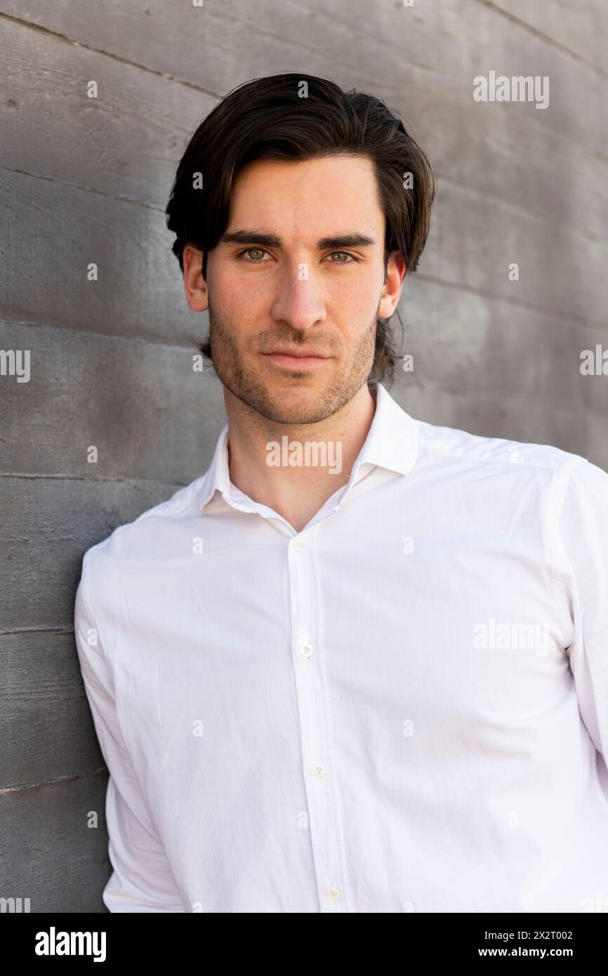 Confident young businessman leaning on wall Stock Photo