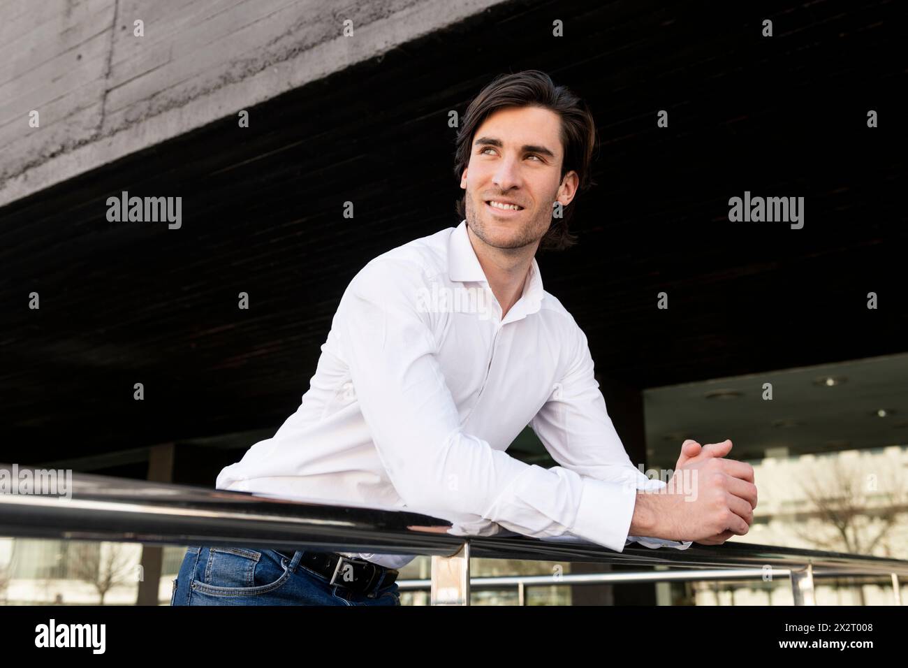 Smiling young businessman leaning on railing Stock Photo