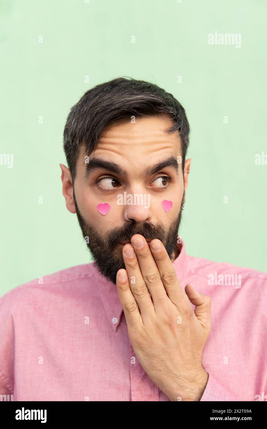 Surprised man covering mouth with hand against mint green background Stock Photo