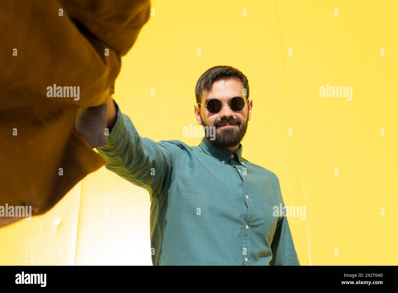 Smiling man wearing sunglasses and holding brown jacket Stock Photo