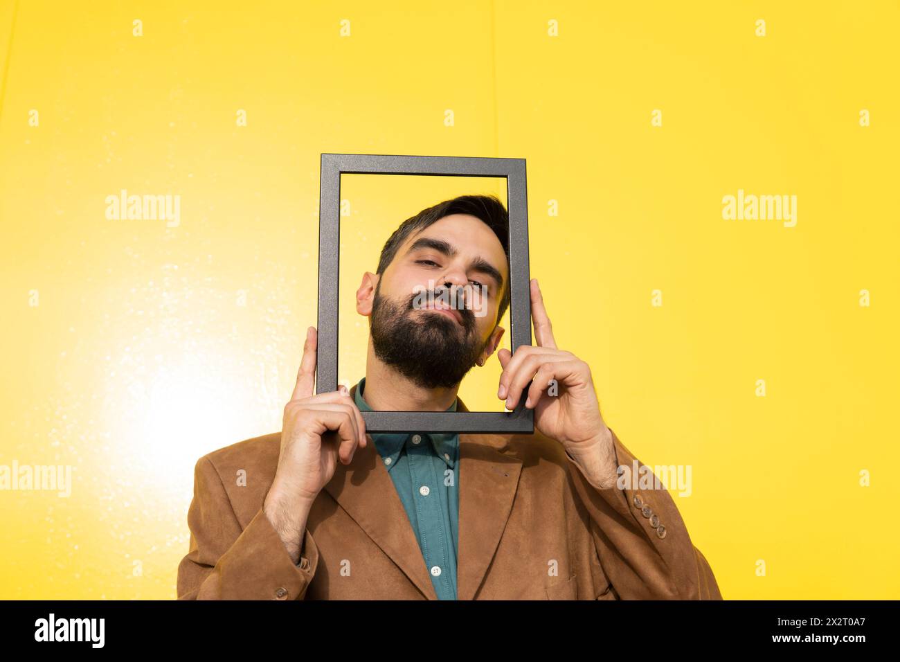 Man wearing brown jacket and looking through photo frame Stock Photo