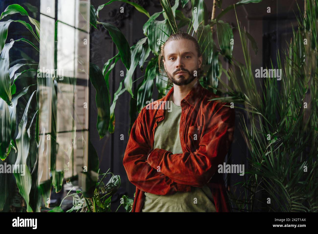 Man standing with arms crossed near plants Stock Photo