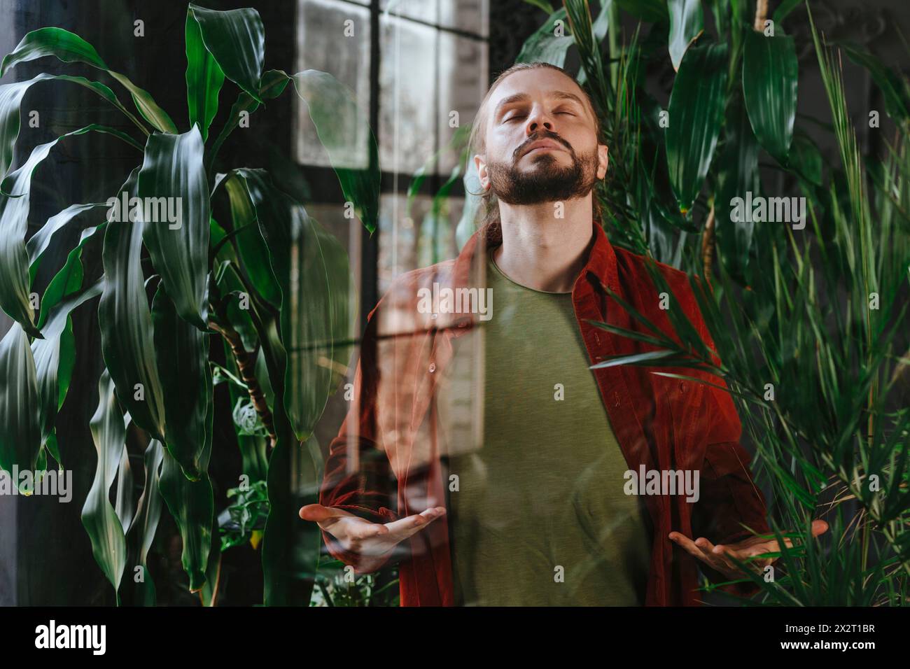 Man practicing breathing exercises near plants Stock Photo