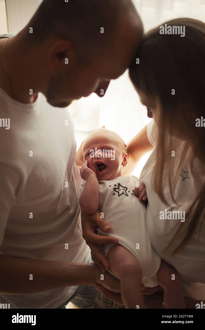 Parent holding baby boy in arms at home Stock Photo
